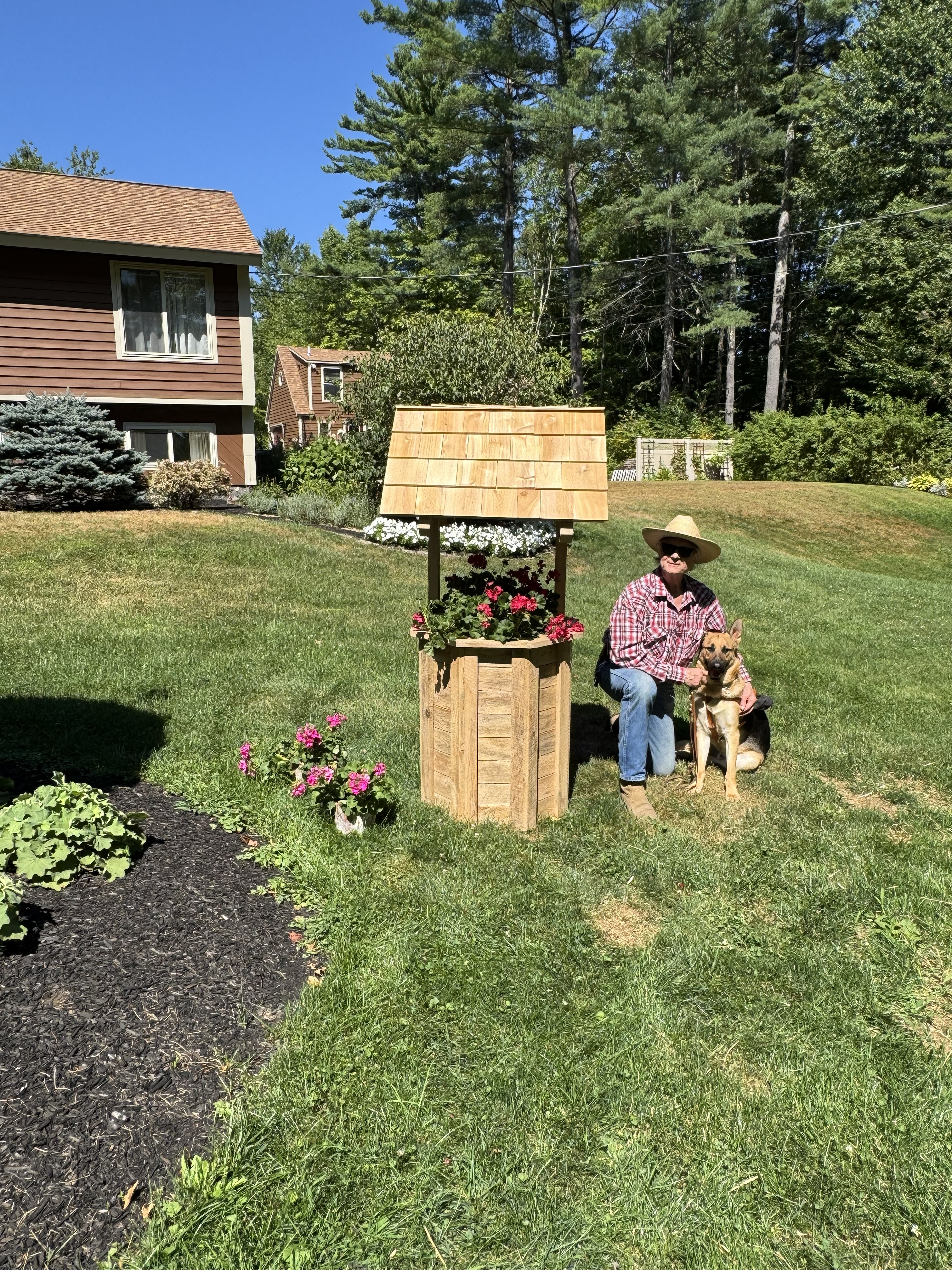 Jim and his guide dog beside a rustic wooden wishing well he built.